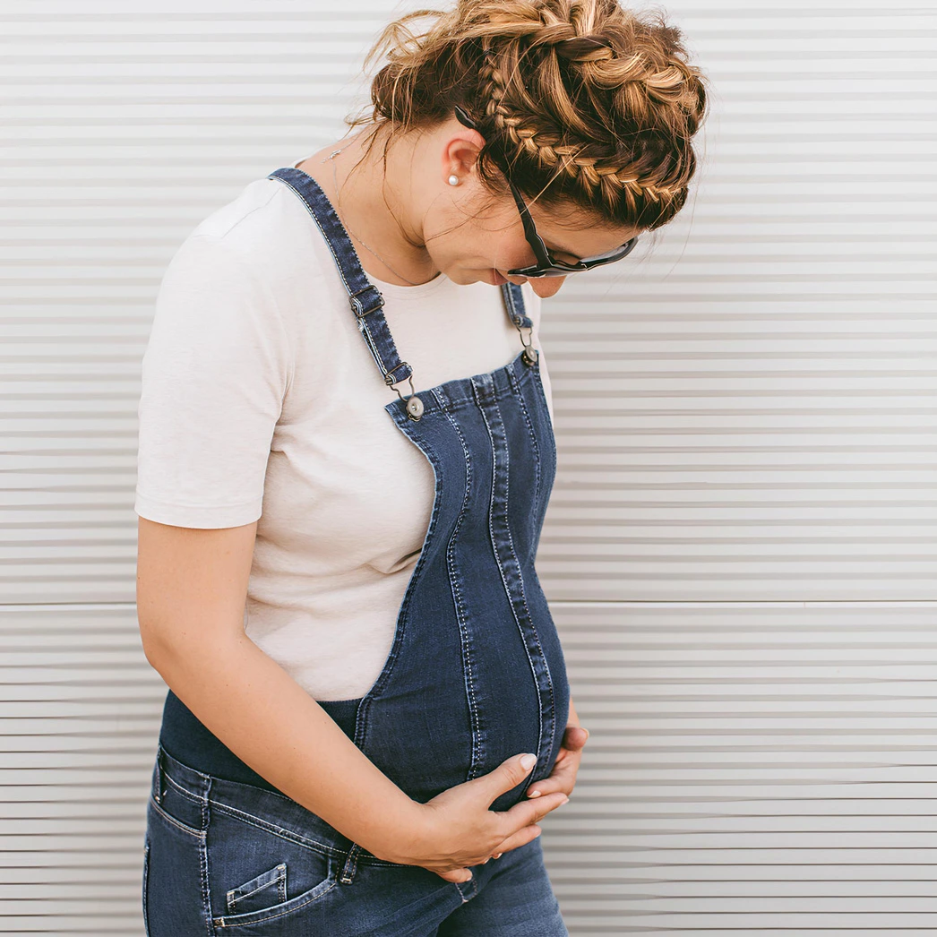 Pregnant woman smiling, holding her belly