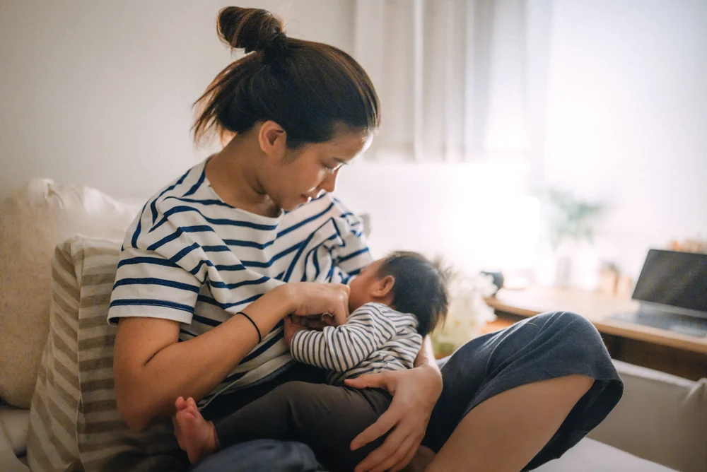 Mother breastfeeding infant on sofa