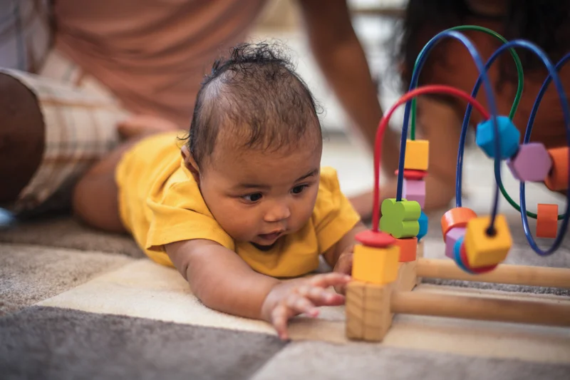Baby reaching for colorful wooden toy