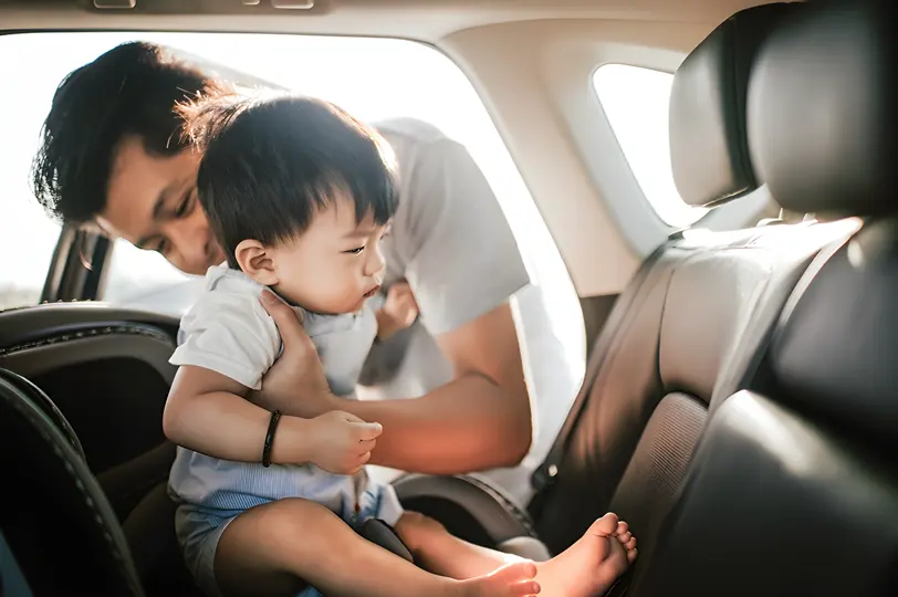 Adult placing baby in rear car seat