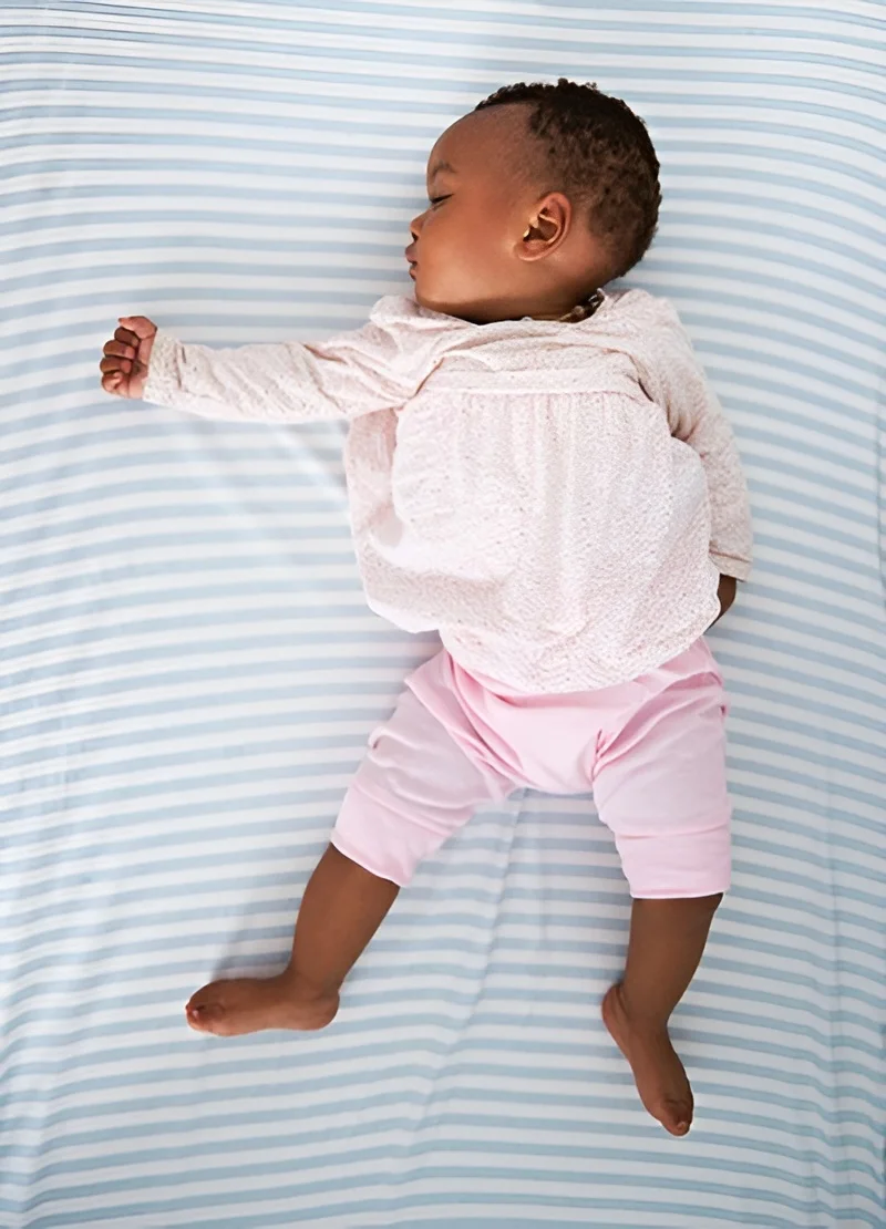 Baby sleeping peacefully on striped bedding
