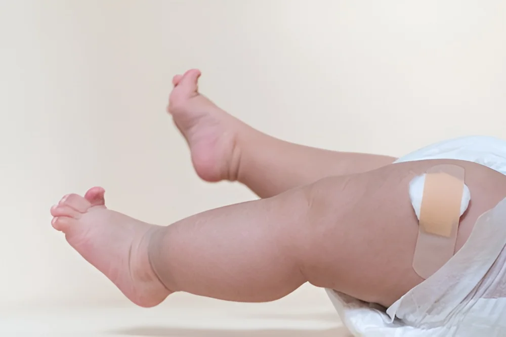 Baby wearing band-aid on leg, lying down
