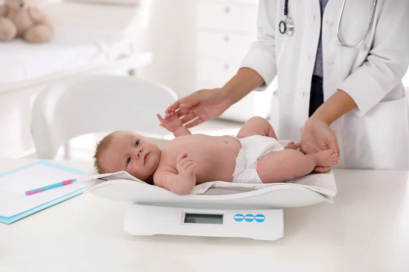 Baby being weighed on digital scale by doctor