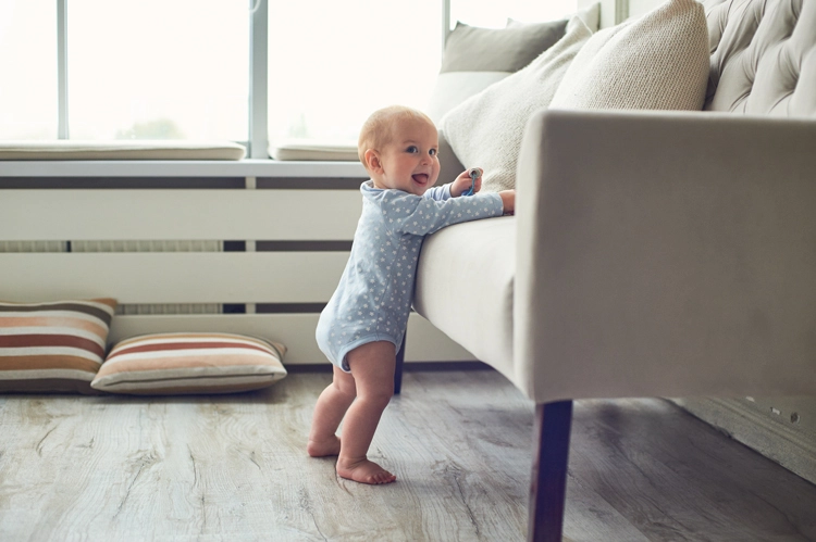 Baby standing and holding onto a sofa