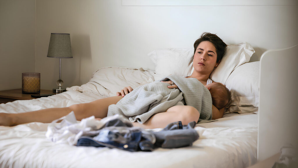 Mother breastfeeding baby while resting on bed