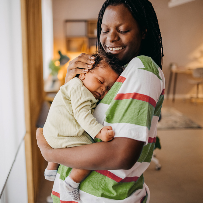 Mother holding sleeping baby lovingly indoors