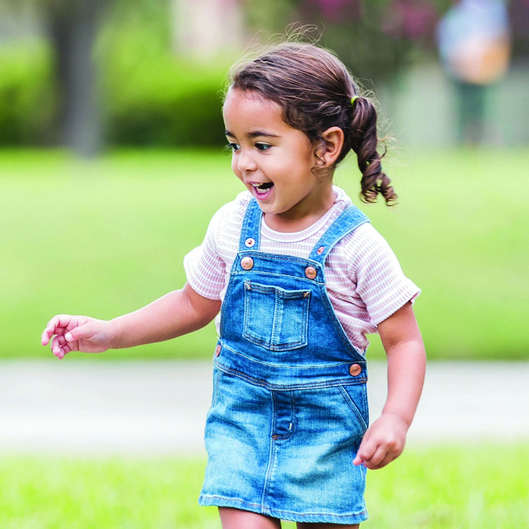 Girl smiling and playing outside in overalls