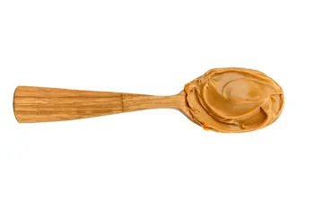 Wooden spoon topped with creamy peanut butter
