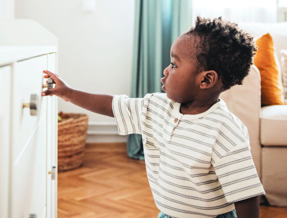 Curious toddler reaching for cabinet knob