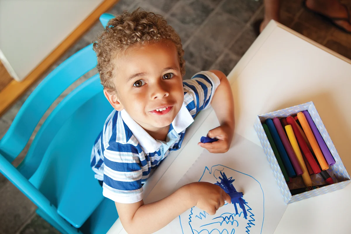Boy coloring at table with crayons