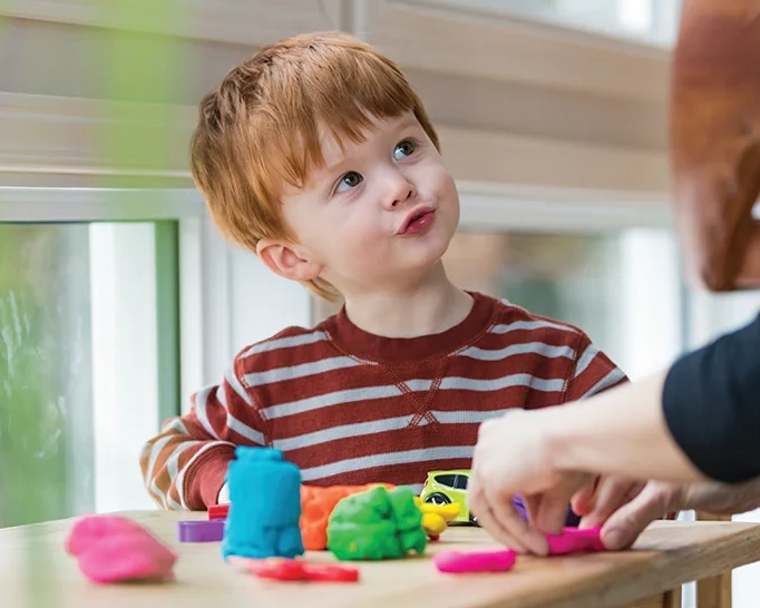 Child playing with colorful clay indoors