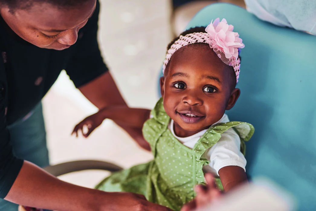 Child in polka dot dress, being guided by adult