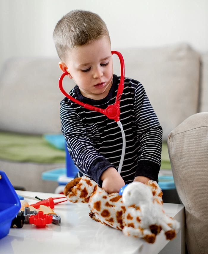 Child playing doctor with toy stethoscope and giraffe