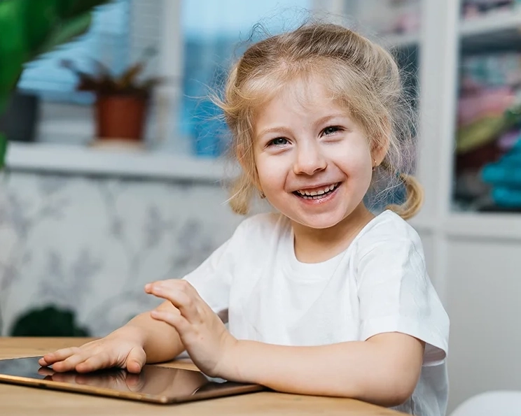 Smiling child using a tablet at a table