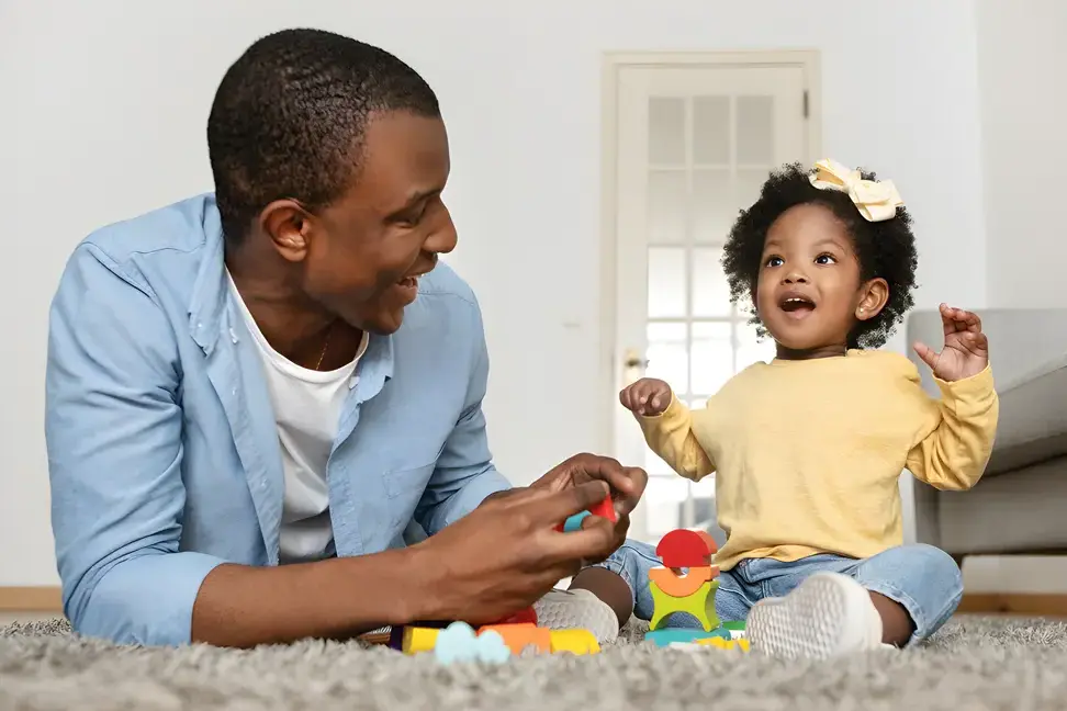 Father and daughter playing with toys on carpet
