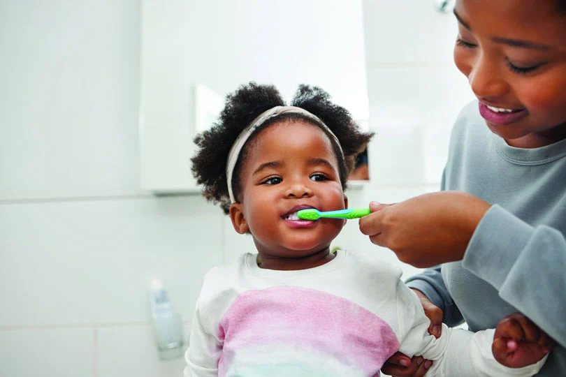 Mom brushing toddlers teeth in bathroom
