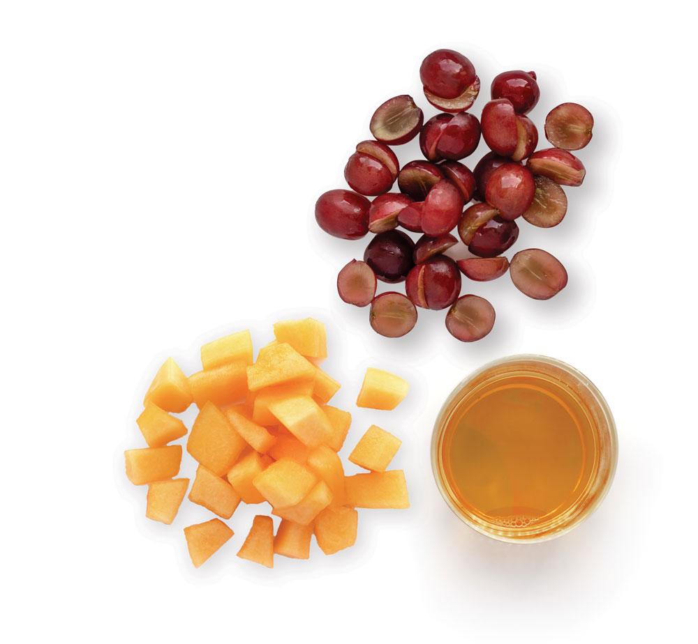 Grapes, diced cantaloupe, and juice arranged neatly