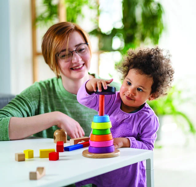 Mother and child playing with colorful stacking toy