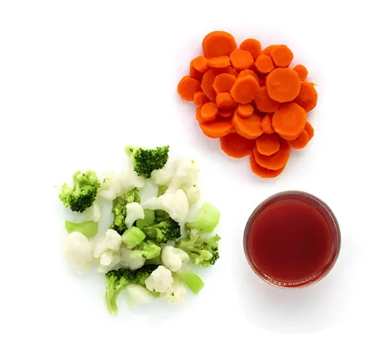 Carrot slices, mixed vegetables, and red juice glass