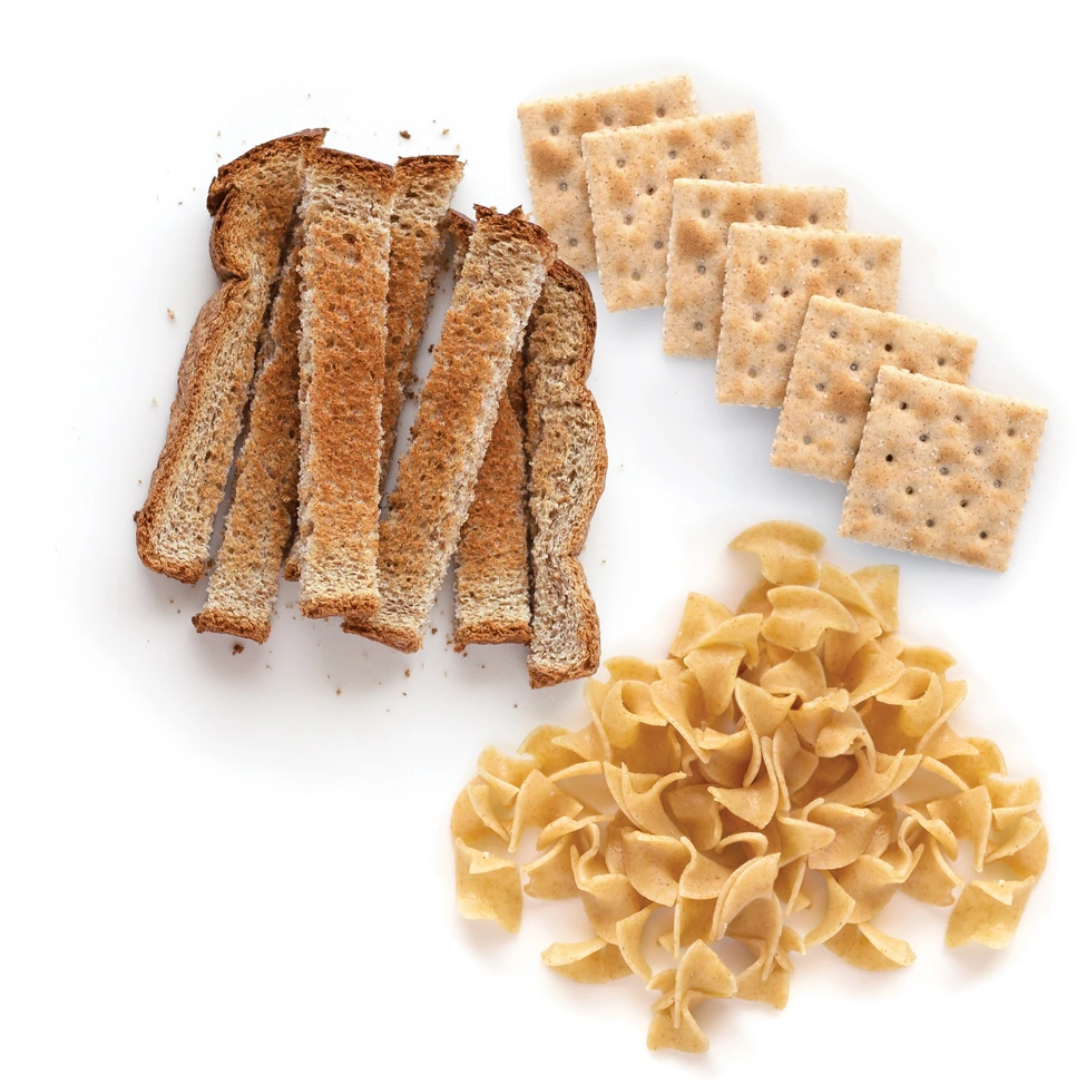 Whole wheat bread, crackers, and pasta arranged on white background.