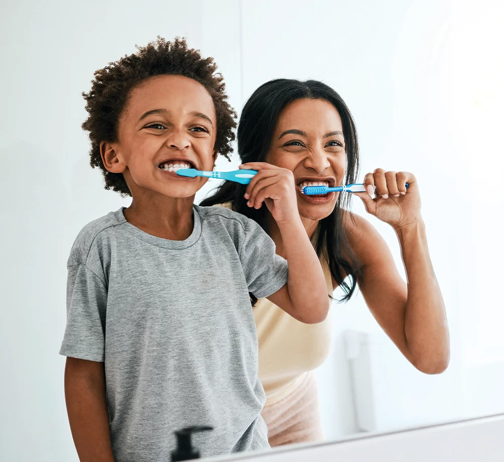 Mother and son brushing teeth together smiling