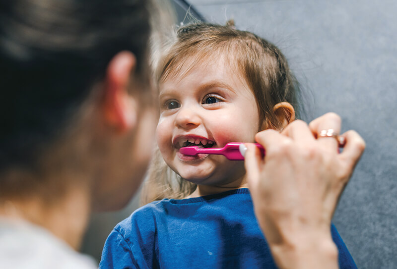 Toddler smiling while getting teeth brushed with toothbrush