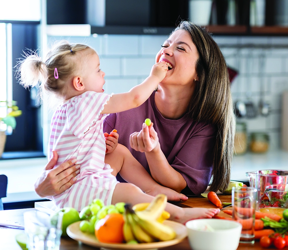 Child feeding mother in a happy kitchen moment